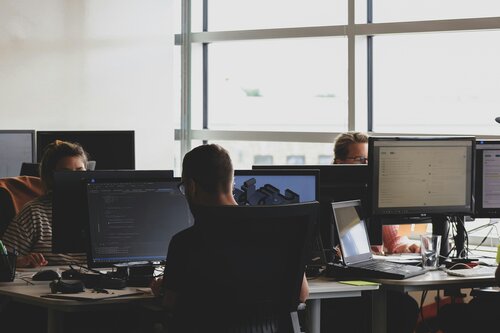 Mitarbeiter Web-End-Solutions sitzen an ihren Schreibtischen vor Monitoren